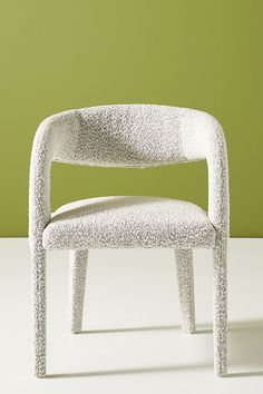 a white chair sitting in front of a green wall