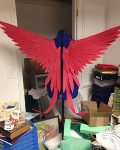 a large red and blue bird statue in a room with boxes on the floor next to it