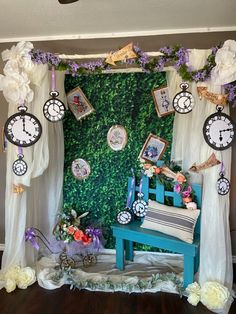 a blue bench sitting in front of a green wall with clocks on it's sides