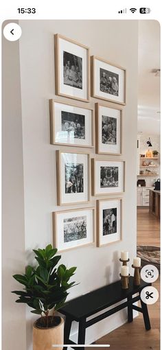 a black bench sitting in front of a white wall with pictures hanging on the wall