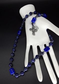 The Deep Blue Irish Anglican Rosary is a beautiful rosary that radiates the seven seas and provides you with a calming effect while praying. The rosary is made of Swarovski Crystals, Lapis lazuli and Jade gemstones (which have been cleansed and purified) while a Stainless Silver Cross completes the rosary. Finally, the rosary has been blessed by the church. Rosary: Anglican configuration Blessed: Yes About the Rosary: The Rosary has a Cross, an Invitatory bead, 4 sets of 7 beads that are called Blue Crucifix Necklace For Spiritual Wear, Blue Crucifix Necklace For Spiritual Purposes, Blue Cross Spiritual Necklace, Blue Rosary With 8mm Beads For Healing, Blue Rosary With Round Beads For Healing, Blue Spiritual Rosary With Gemstone Beads, Spiritual Blue Rosary With Gemstone Beads, Blue Gemstone Beads Rosary For Spiritual Use, Blue Rosary For Healing