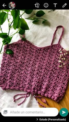 a crocheted bag sitting on top of a wooden table next to a plant