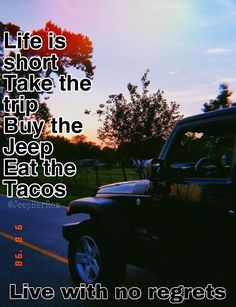 a black jeep parked on the side of a road next to a park with trees