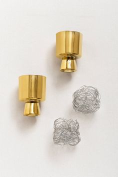 three pieces of wire sitting next to each other on a white surface with gold colored fixtures