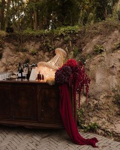 a wooden table topped with lots of bottles and flowers on top of a stone floor