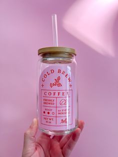 a hand holding a glass jar with a straw in it that says cold berry coffee