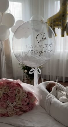 a bouquet of roses sits on the bed next to a baby's name balloon