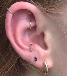 a close up of a person's ear with three piercings