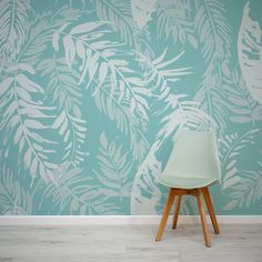 a white chair sitting in front of a blue wall with leaves painted on the wall