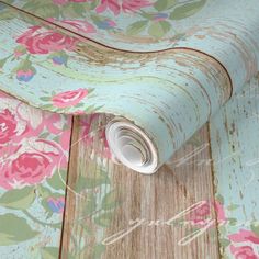 an old wallpaper with pink flowers on it is laying on the floor next to a roll of tape