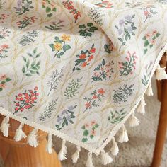 a table with a white and green floral design on it, sitting next to a wooden chair