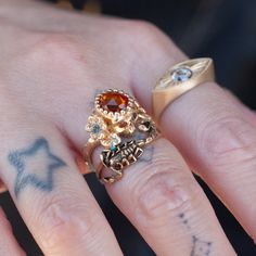 A garden snake wraps around a skull resting in a bed of flowers in an allegory come to life that you can wear on your finger. Named Nozarashi, Japanese for "weather beaten bones" in a twist on traditional memento mori rings. A snake for shedding old ways, flowers for growth, and an open minded skull to live life to the fullest. One of a kind and handmade in solid 14k yellow gold by Nick Potash in his Maui, Hawaii Studio. Orange sapphire brain (1.2ct), light blue sapphire flowers, orange sapphire skull eyes and a single turquoise snake eye. Size 6 and not resizable. Each Nozarashi Skull ring comes in a traditional Japanese Paulownia wood box designed to protect heirlooms from the environment, stamped with Nick's two hanko. Skull Eyes, Garden Snake, Memento Mori Ring, Bed Of Flowers, Charm Bracelet Watch, Light Blue Sapphire, Paulownia Wood, Old Ways, Flowers Orange