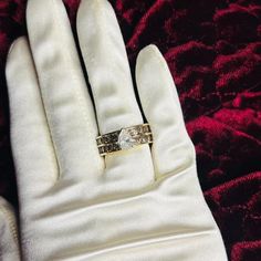 a white glove with a gold ring on it's finger and a red velvet background