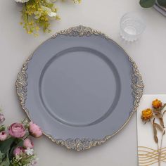 a gray plate sitting on top of a white table next to flowers and napkins