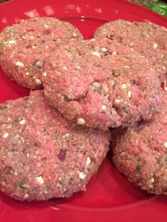 four hamburger patties on a red plate