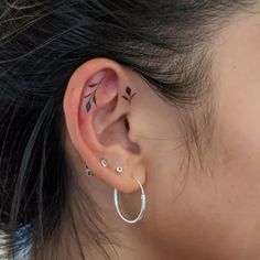 a woman with tattoos on her left ear and behind the ear is a hoop earrings