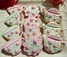 decorated cookies are arranged on a plate with pink and green decorations in the shape of teapots