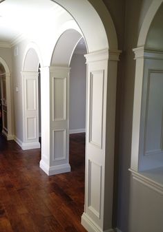 an archway between two rooms with wood floors and hard wood flooring on the other side