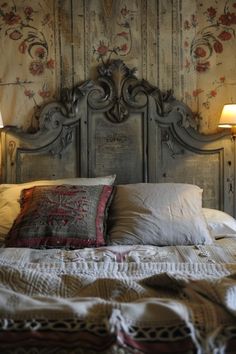 Vintage-style bed with ornate headboard, surrounded by floral wallpaper and lit by two small wall lamps. Dark Academia Headboard, Goth Headboard, Unique Headboard Ideas