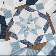 a table topped with blue and white quilts on top of a wooden floor next to a piece of paper