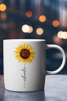 a white coffee mug with a yellow sunflower painted on the side and words written in cursive writing