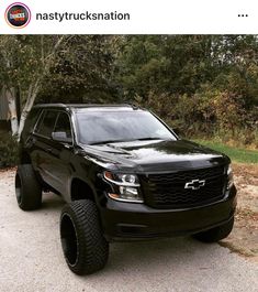 a black truck parked in front of some trees