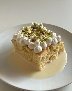 a piece of cake with marshmallows and pistachio on top sits on a white plate