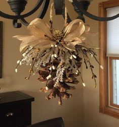 a chandelier hanging from the ceiling with pine cones and other decorations on it