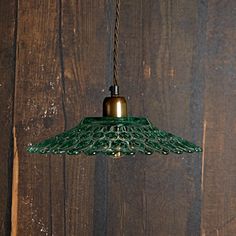 a green glass light hanging from a wooden wall