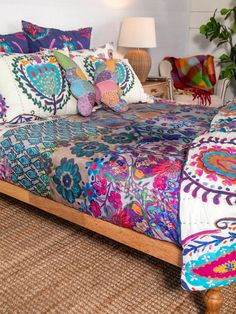 a bed with colorful bedspread and pillows on it in a room next to a lamp