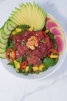 a white bowl filled with lots of food on top of a table next to watermelon slices