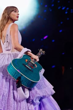 a woman in a purple dress holding a guitar