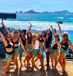 a group of women standing next to each other near the ocean