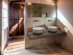 two white bowls sit on a counter in front of a mirror and wooden paneled door