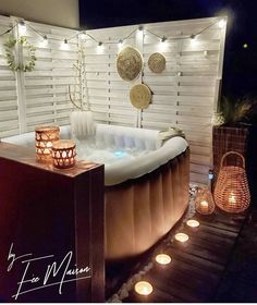 an outdoor hot tub with candles lit up on the side and lights hanging above it