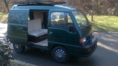 a green van parked on the side of a road with its door open and luggage in the back