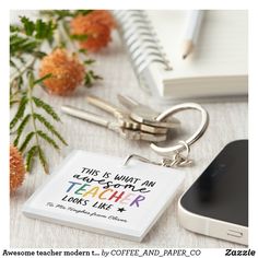 a keychain with words written on it next to a cell phone and flowers