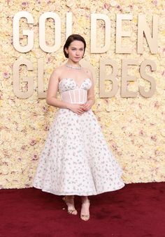 a woman in a white dress standing on a red carpet with the words go golden globes