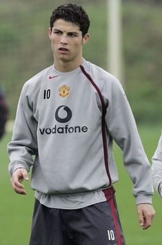 a young man standing on top of a soccer field wearing a gray shirt and black shorts