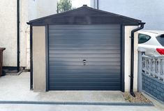 a car parked in front of a garage with a metal door on the side of it