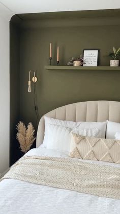 a bed with white sheets and pillows next to a shelf on the wall above it