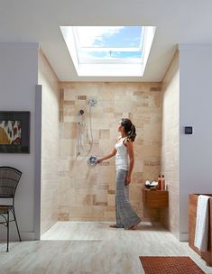 a woman is standing in the shower and looking up at the skylight