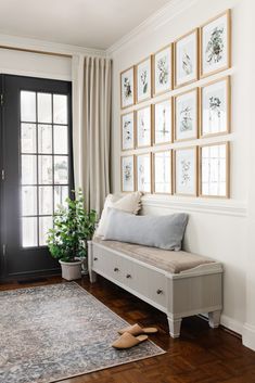 a living room with pictures on the wall and a bench in front of a door