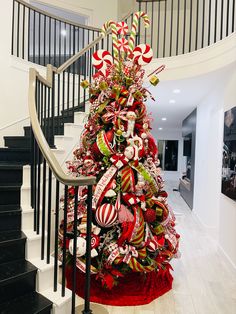 a christmas tree decorated with candy canes and bows on the stairs in a house