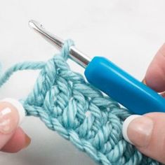 someone is crocheting the stitchs together with a blue crochet hook