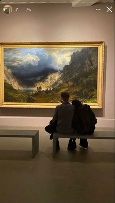 two people sitting on a bench in front of a painting with mountains and clouds behind them