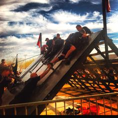 several men are climbing up the side of a ramp on a roller coaster at an amusement park