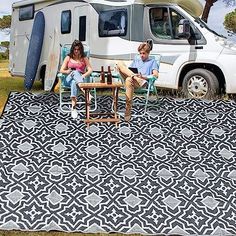 two people sitting at a table in front of an rv