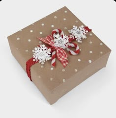 a brown box with snowflakes on it and a red ribbon around the bow