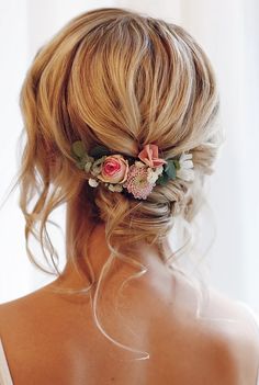 a woman with blonde hair and flowers in her hair is wearing a flowered updo